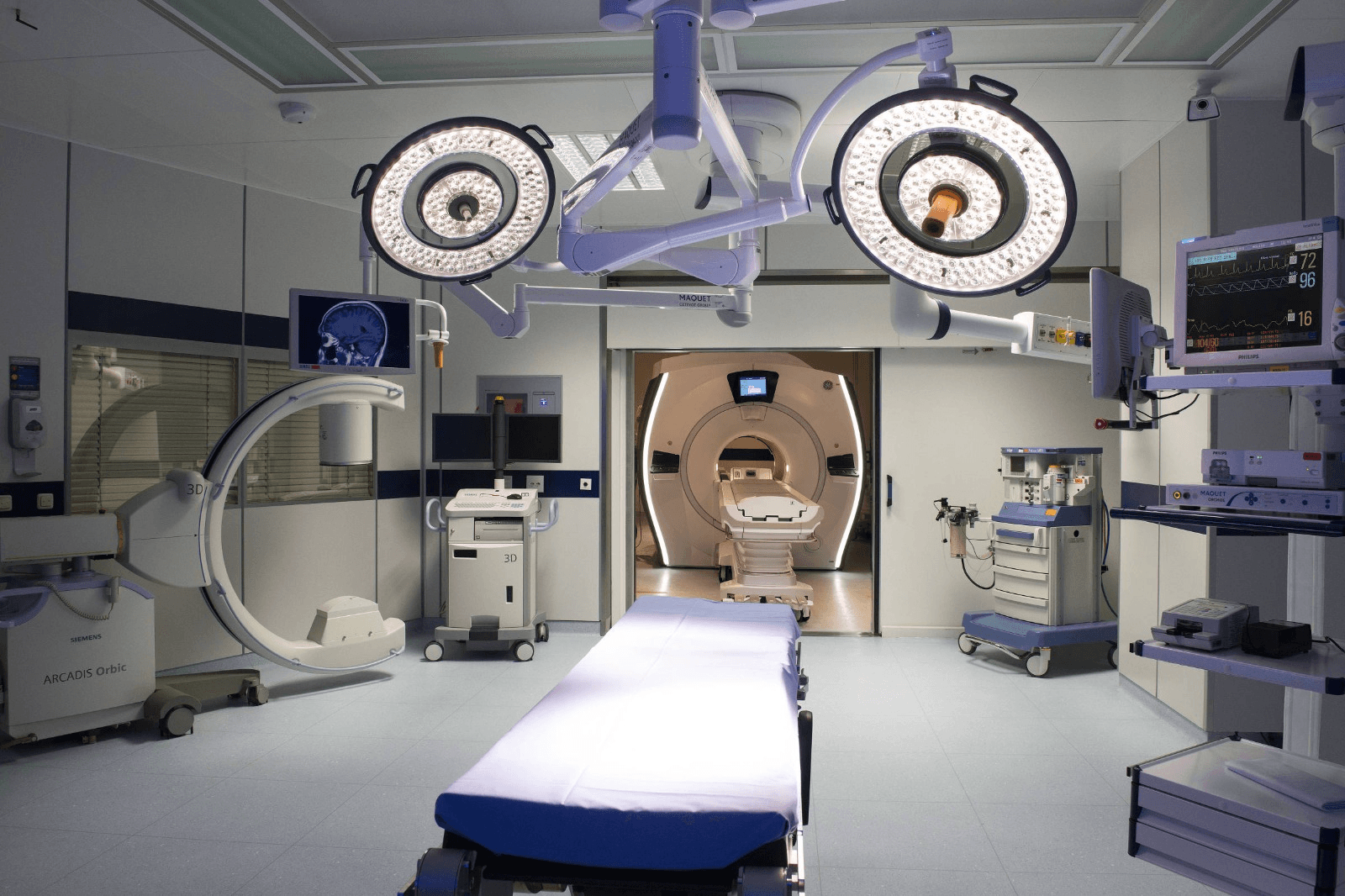 Sala cirúrgica híbrida com arco cirúrgico, monitores e ressonância
